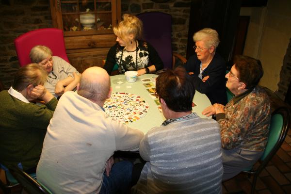 Des personnes agées jouent à des jeux de société autour d'une table ronde à la maison de repos en famille