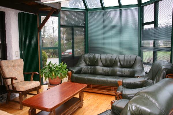 La maison de repos en famille a un salon très lumineux avec de grands fauteuils et canapés verts